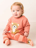 Baby wearing a pink outfit with a Jaguar print design on a light background